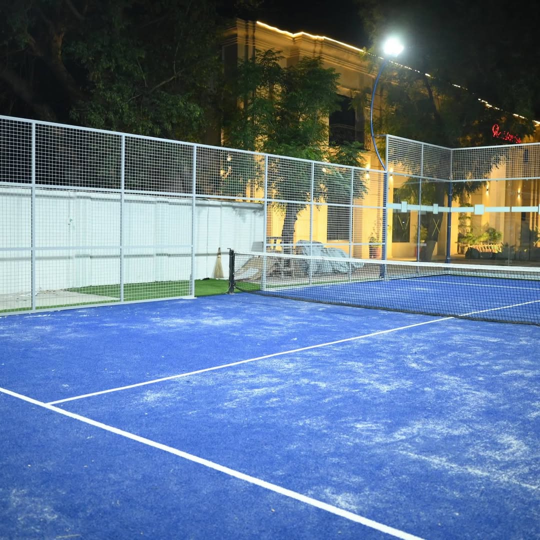 View across the padel net toward the glass wall